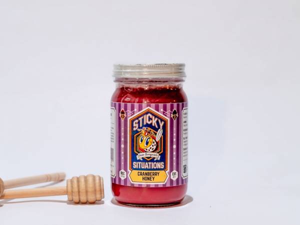 8 oz cranberry honey jar with honey dipper to left