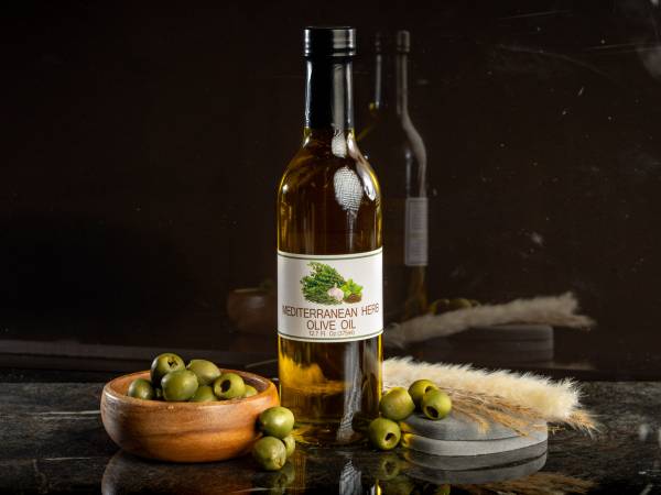 12.7 ounce bottle of mediterranean herb olive oil with olives to left and right