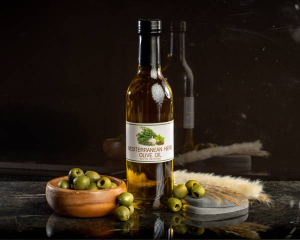 12.7 ounce bottle of mediterranean herb olive oil with olives to left and right